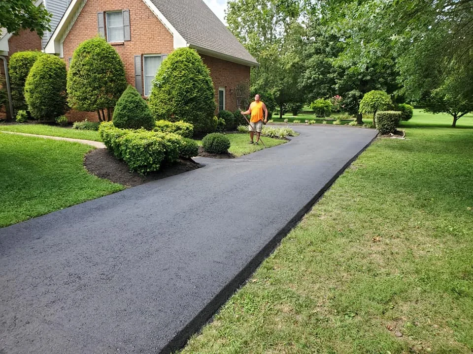 Asphalt resurfacing finished on a home driveway lined with trimmed shrubs