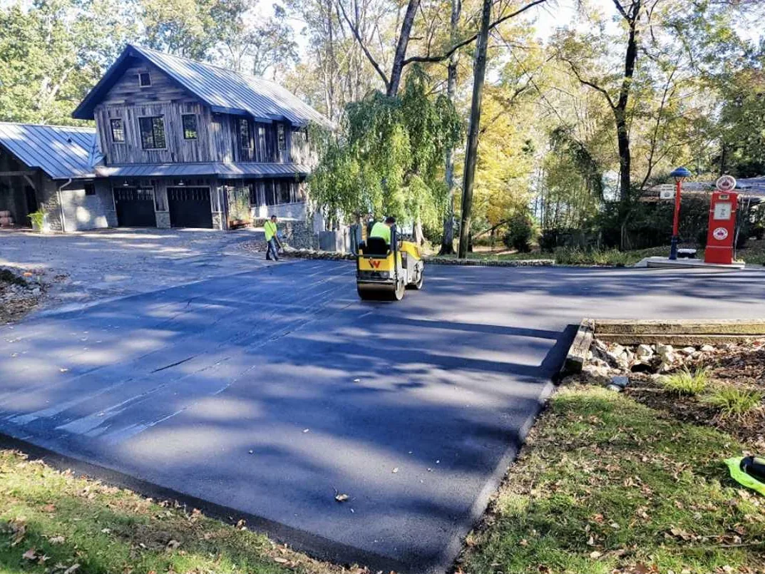 Asphalt resurfacing at a home driveway with a roller compacting the new layer