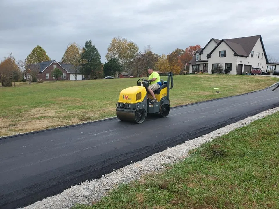 Asphalt resurfacing with a roller compacting fresh hot mix on a long home driveway