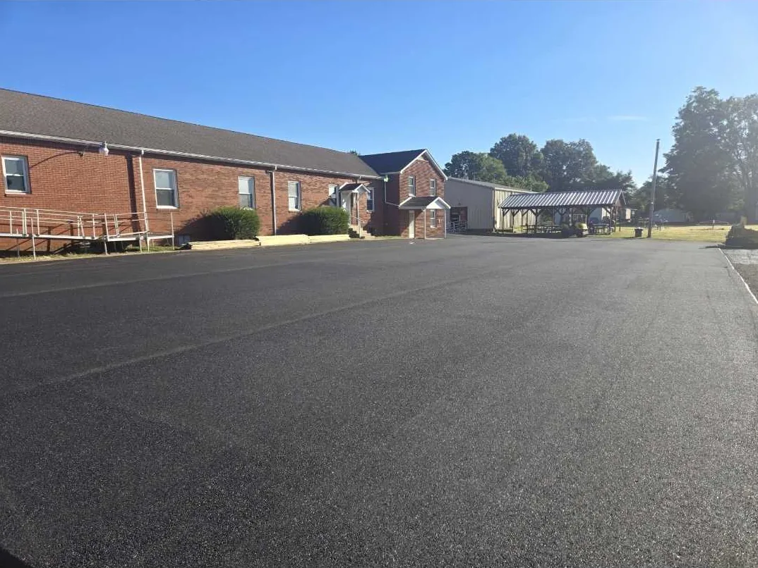 Parking lot paving finished beside a brick building with an access ramp