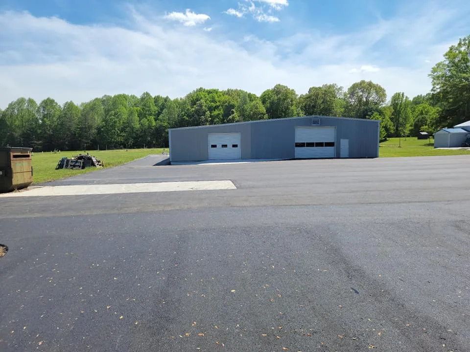 Parking lot paving in front of a metal shop building with two overhead doors