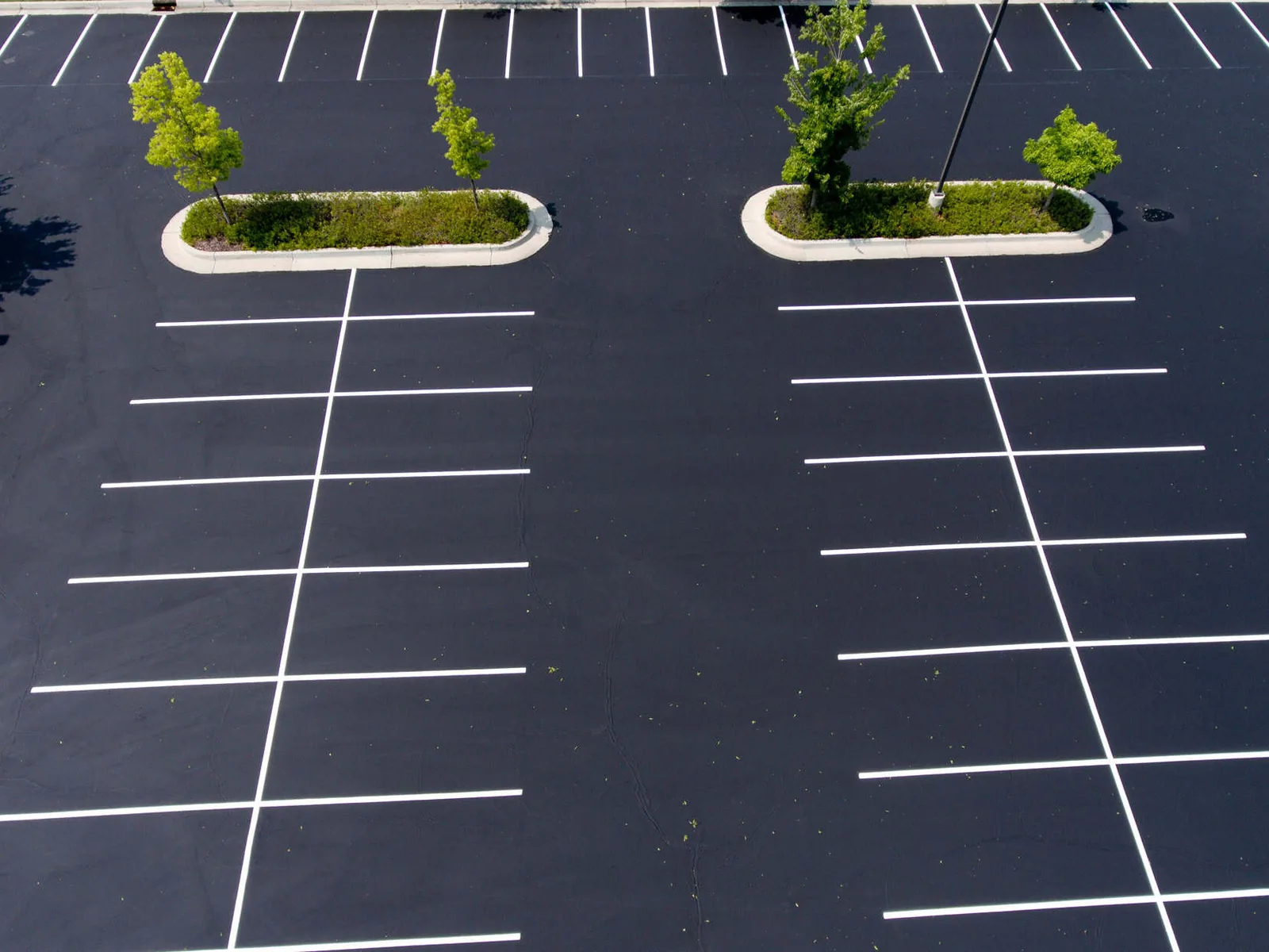 Aerial view of a sealed asphalt lot with new white stall lines, parking lot striping
