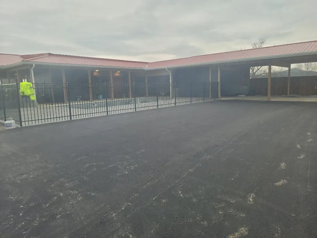 Freshly paved lot beside a covered building, ready for parking lot striping