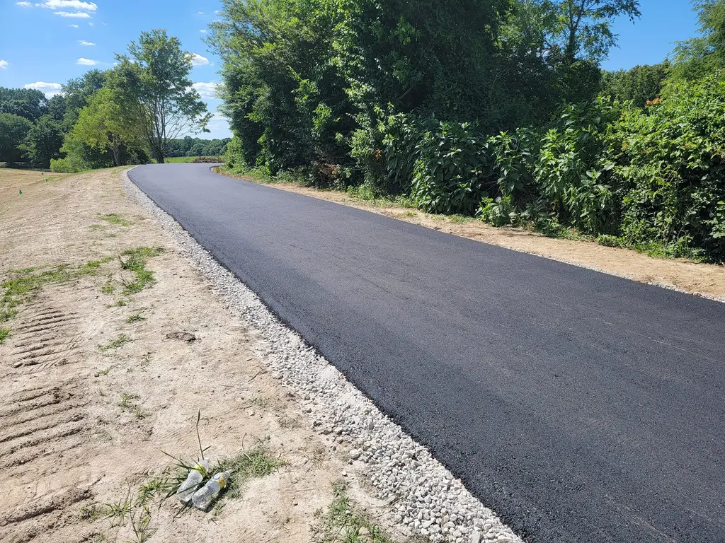 Private road paving on a long new asphalt lane with a crushed stone shoulder