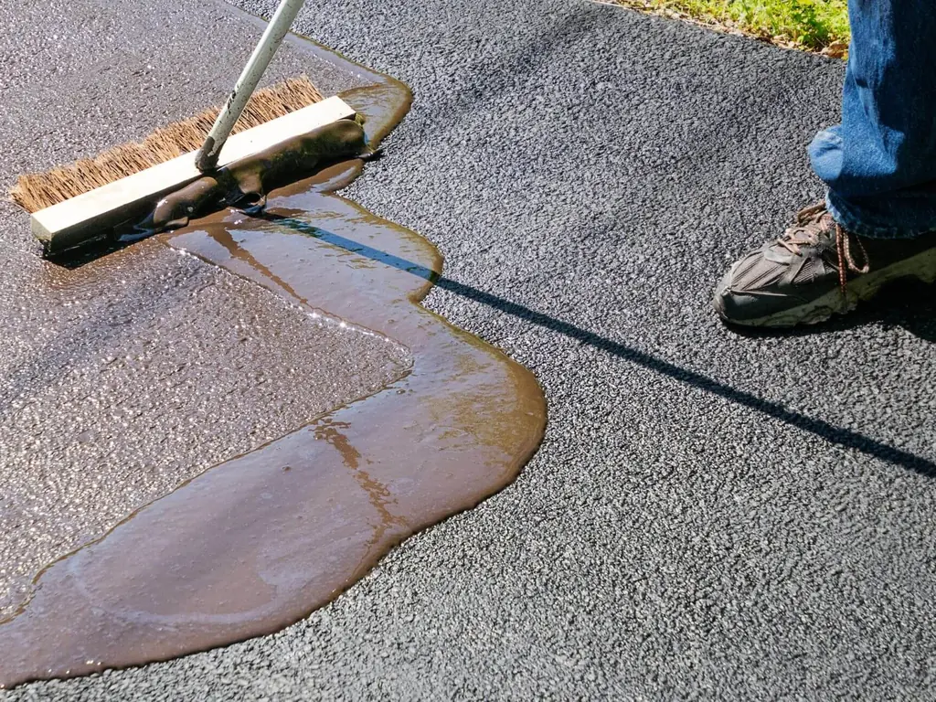 Push broom working sealer into an asphalt driveway, sealcoating