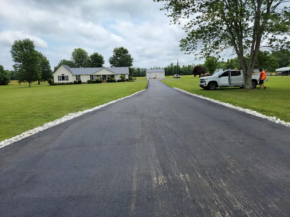 Straight asphalt driveway edged with white rock, ready for sealcoating